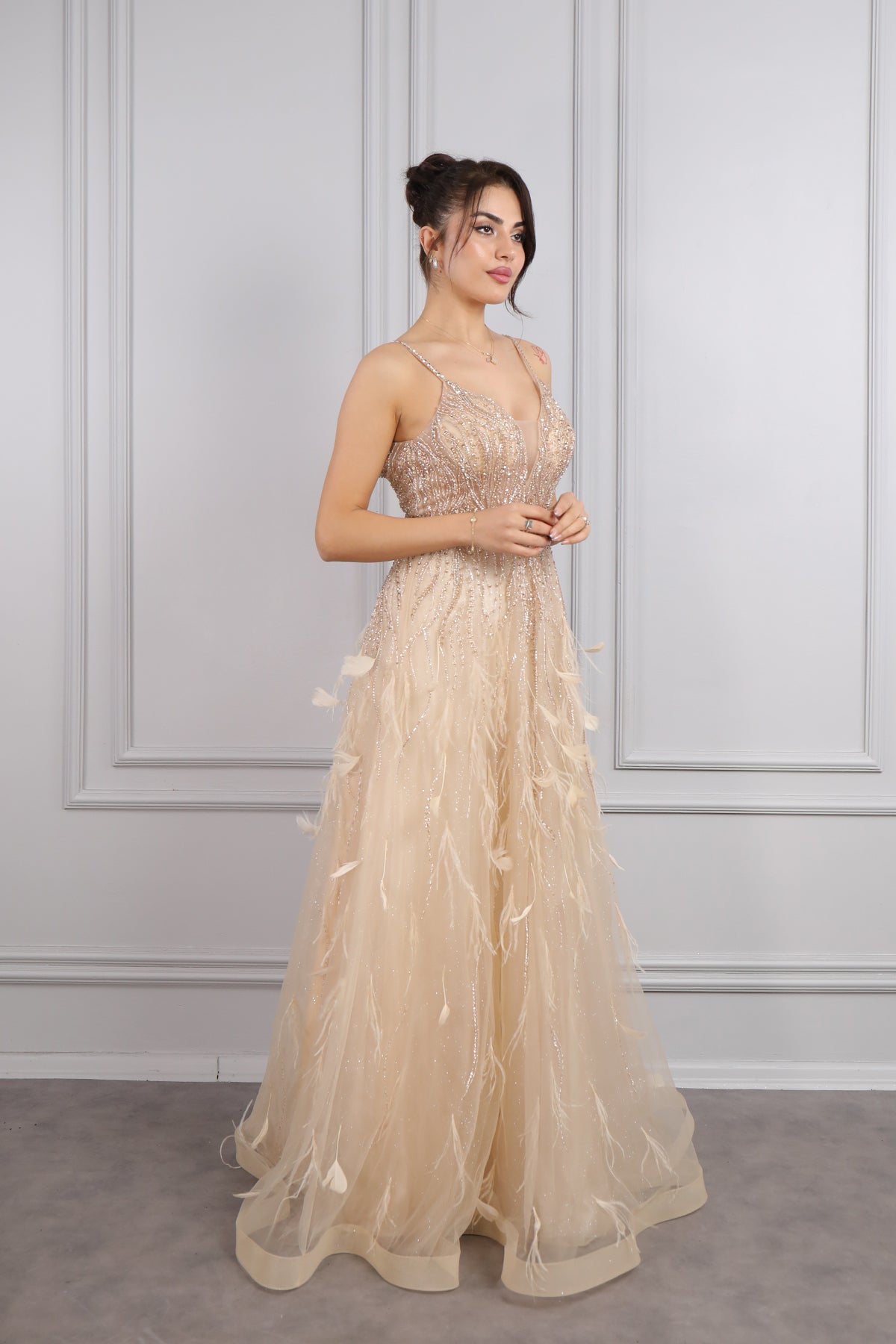 فستان سهرة بحمالات رفيعة وفتحة كبيرة في الصدر مع تفاصيل ريش من "المجموعة الخاصة" -ذهبي